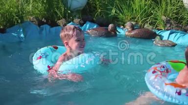 两个小朋友在一个小池塘里游泳.. 兄妹笑，泼水.. 孩子们在炎热的夏日游泳